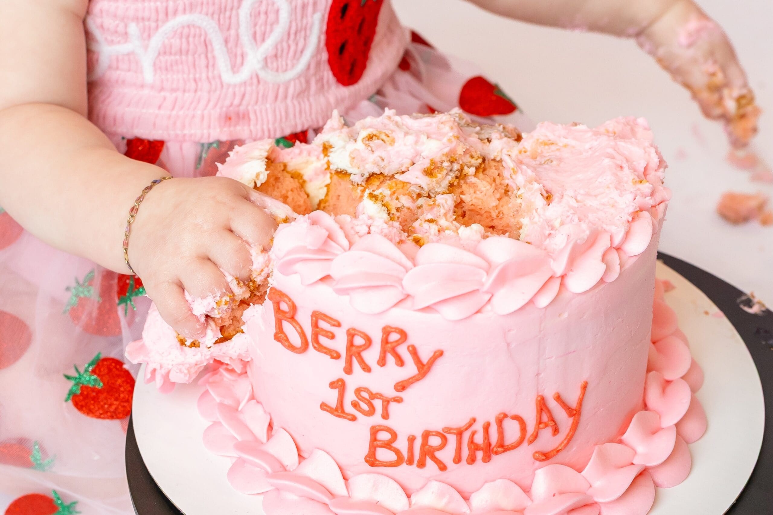 One-year-old girl smashing her cake during her personalized first birthday photoshoot