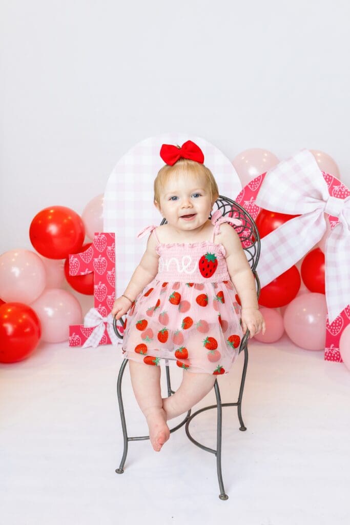 One-year-old girl smiling during her first birthday milestone photoshoot