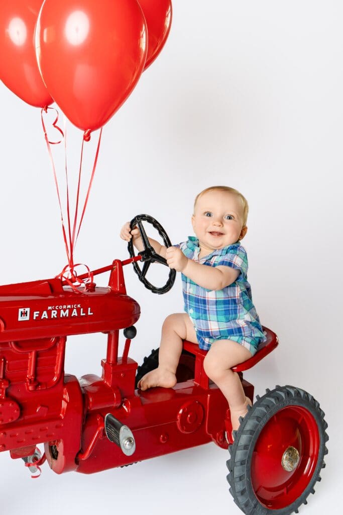 One-year-old boy smiling during his first birthday milestone photoshoot with tractor in joplin mo