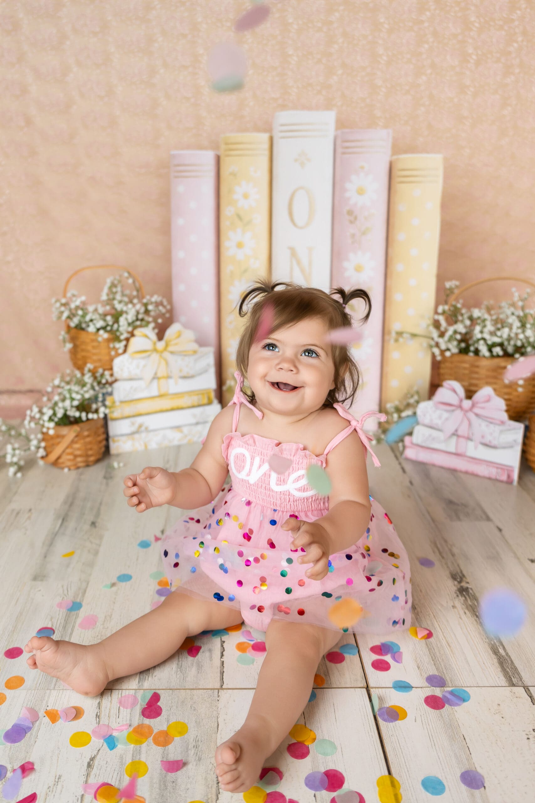 toddler smiling with dropping confetti during custom first birthday photo session in joplin mo
