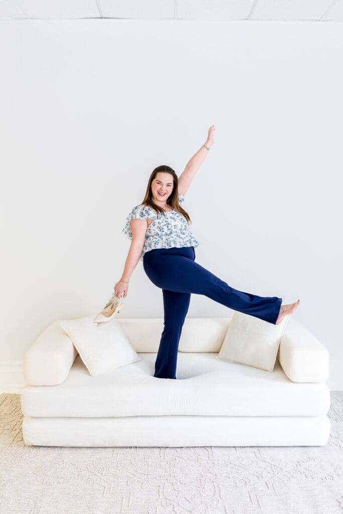 Business coach doing a celebratory kick on couch during branding photoshoot in pittsburg ks