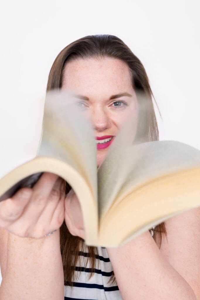 Brand photography session showing entrepreneur smiling with flipping of coaching book in Joplin MO